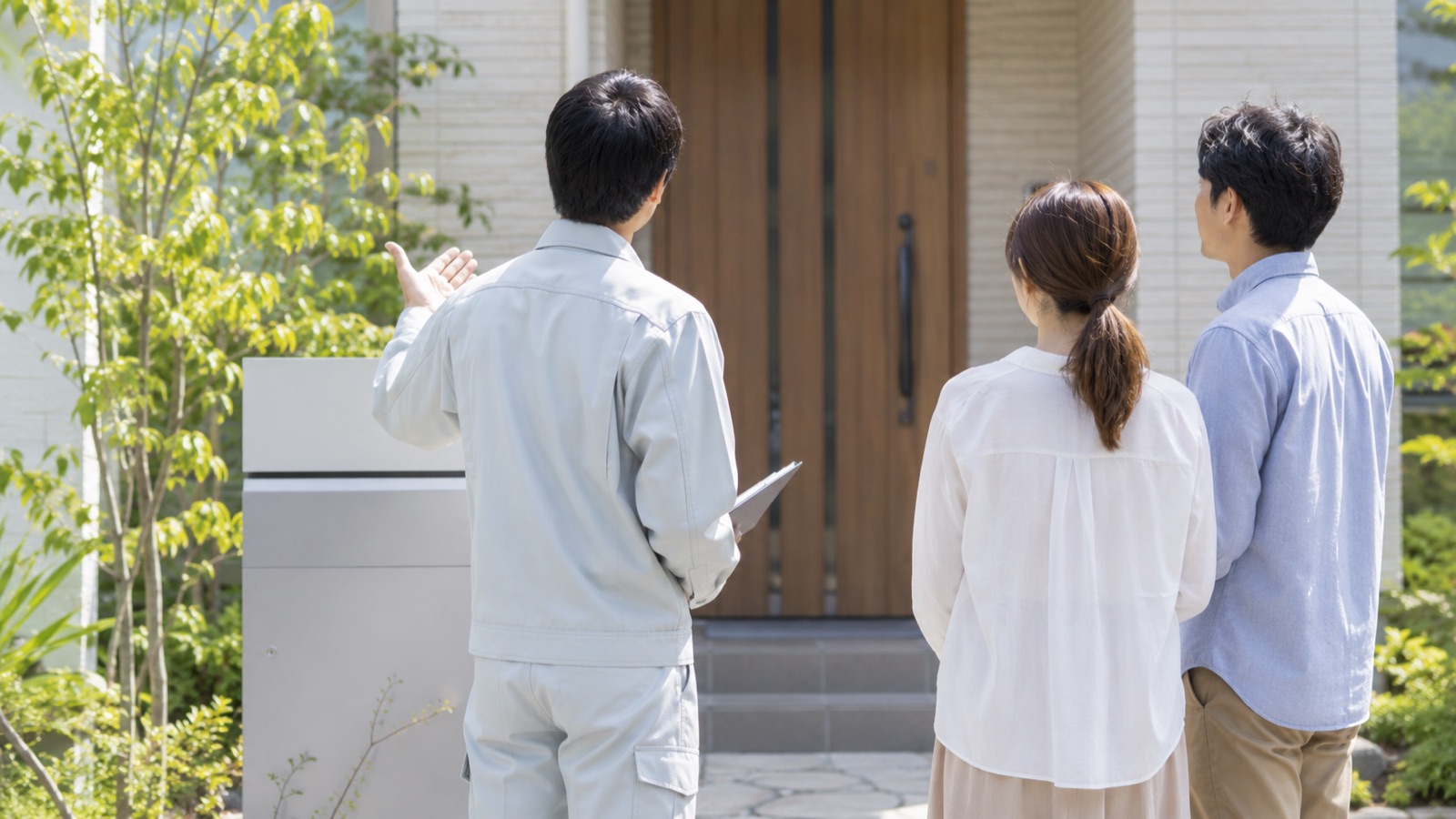 作業服の職人が住宅の玄関先でお客様に説明している様子